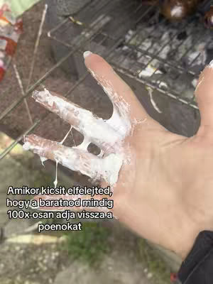 A person's hand is seen covered in a white, viscous substance, likely cream or a similar material. The hand is held up against a background that includes a metal grill and a blurred, outdoor setting. A text overlay explains the context.