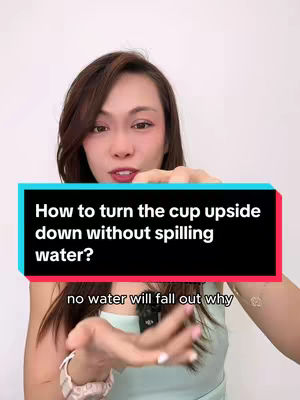 A woman with brown hair looks at the camera smiling with a light-blue top and she holds a large rectangular black box where are written the following question: “How to turn the cup upside down without spilling water?” There is also a smaller rectangle labeled text under the box and it says, “no water will fall out why”. White background.