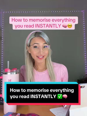 A woman with long blonde hair and glasses is smiling at the camera. She wears a pink sweater and is seated in front of a plain gray wall. Additional elements include the text overlay with the video’s title, surrounded by purple fairy lights. There are pink and white items visible on the desk in front of her.