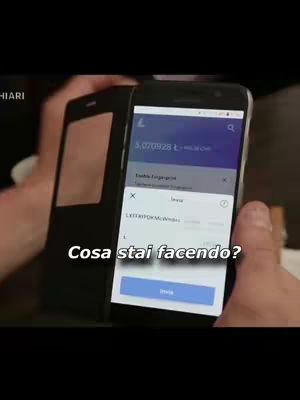 A person's hands are holding a dark phone case with a phone inside displaying a Litecoin transaction with the text "Cosa Stai Facendo?" overlaid.