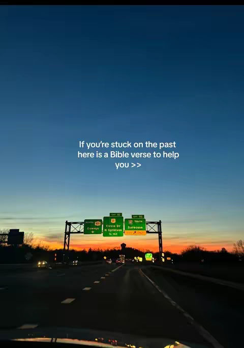 The image captures a sunset seen from a moving vehicle, likely during golden hour. The sky transitions from a deep blue at the top to vibrant oranges and yellows near the horizon. Silhouetted objects, including what appears to be a highway overpass with signs indicating exits, are visible against the colorful sky. The road has lanes for traffic, and the overall composition is divided roughly in half by the horizon line. Text is overlaid, offering a Bible verse for a specific situation.