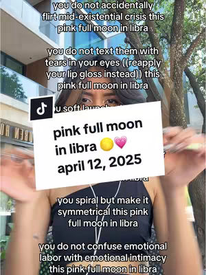 A woman holds up a sign with text related to a full moon and astrological themes, while the image includes overlaid text that discusses Libra’s full moon, with a background blur of buildings and foliage.