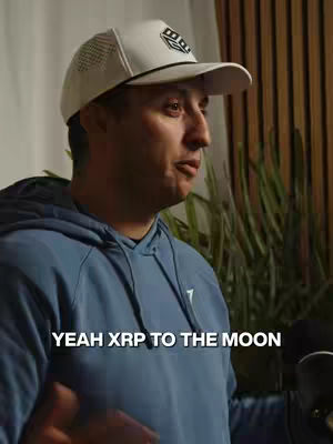 A man in a blue hoodie and white cap is speaking. The image has text at the bottom that says, "YEAH XRP TO THE MOON".