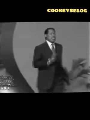 A grayscale image shows a man in a suit speaking on a stage with a blurred background. The top right corner features the text "cookeysblog" in yellow. Additional text is visible, but not fully readable.