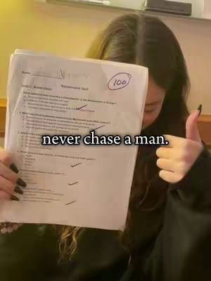 A woman holding a test paper with a score of 100, giving a thumbs up. Overlay text reads, 'never chase a man.'