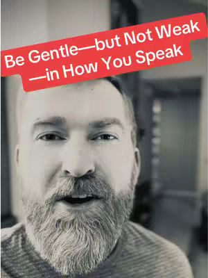A grayscale selfie-style image featuring a man with a full beard in the foreground. Above him, a red rectangular text overlay reads: 'Be Gentle—but Not Weak—in How You Speak.' The background is blurred, suggesting an indoor setting.