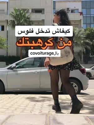 The cover image shows a woman standing next to a silver car on a brick-paved sidewalk. She is facing away from the camera with her back to the viewer. She is wearing a black skirt, black tights, black boots, and a tan top. Overlayed on the image is a white rectangle containing the text. The background includes buildings and palm trees, suggesting an urban or suburban environment.
