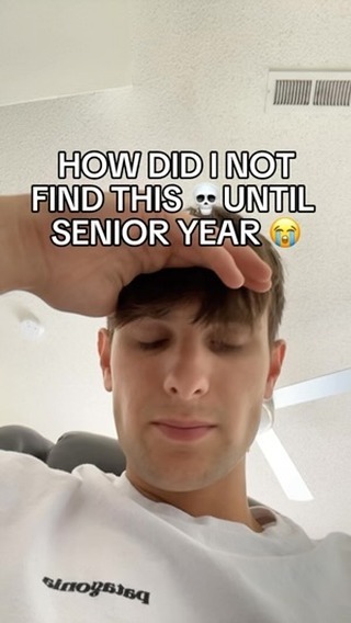 A young man with short brown hair is the main subject. He wears a white t-shirt and looks down with a slightly pensive expression. Above him, a text overlay in a bold, sans-serif font reads, "HOW DID I NOT FIND THIS UNTIL SENIOR YEAR" with a skull emoji. Overall, the image has a casual, slightly remorseful vibe.