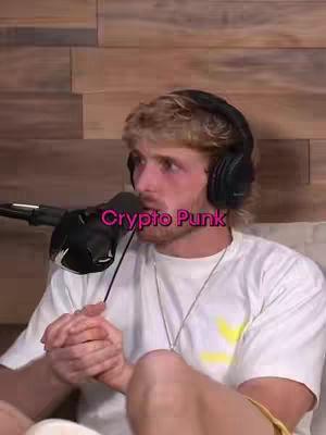 A medium shot shows a fair-skinned man speaking into a microphone. He has short, highlighted blonde hair, a slight beard, and is wearing a white t-shirt. Overlaid on the image is pink text that reads 'Crypto Punk.' The background is a wooden panel.