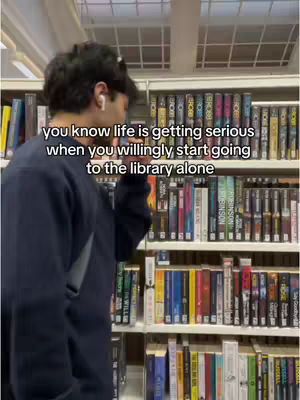 A person stands in front of bookshelves, holding a hand up to their face with text overlayed on the image.