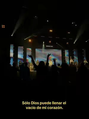 The image shows a darkened stage with bright lights and a blurry audience giving praise. At the bottom is a text overlay that reads 'Sólo Dios puede llenar el vacío de mi corazón.'