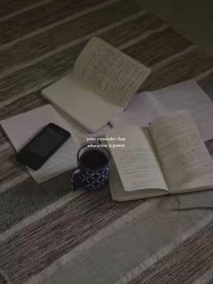 A cozy, dimly lit image featuring a neutral-toned striped blanket as a foreground with scattered elements of a study setup. Open books and loose papers are spread around a dark-colored e-reader and a mug of coffee. The overall aesthetic is intended to create a study atmosphere, likely in a home environment.
