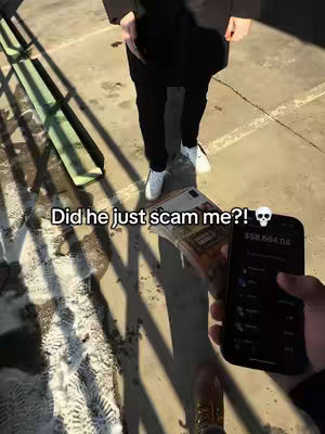 A person in a black coat and black pants stands on a concrete surface. A person holding a phone with an app open displaying numbers and a stack of what appears to be cash as well as a text overlay in the image.