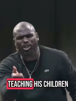 A bald, Black man with a serious expression is pointing at the viewer. He is wearing a black long-sleeve shirt. Text overlaid on the bottom of the image reads, "TEACHING HIS CHILDREN."