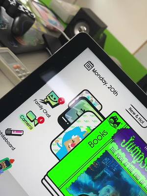 A tablet screen displaying app icons and a book cover titled 'Jumps: The Pool at the End of'. Overlaid on the screen are several app icons, including 'Family Chat' and 'Camera'. The background is blurred, suggesting a setup near other electronic devices.
