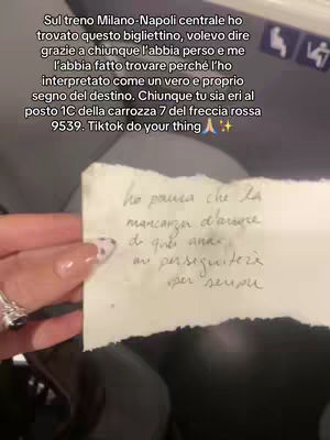 A hand holding a torn piece of paper with handwritten text, a close-up shot focusing on the message and a manicured hand wearing a ring.