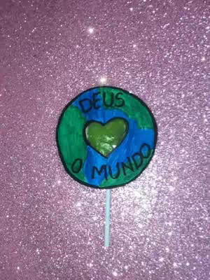 A circular illustration of the Earth with a heart in the center, held on a stick. The background is a sparkly, glittery pink.