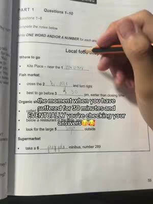 A close-up shot shows a hand holding a pencil, writing on a worksheet with text and fill-in-the-blank segments. The top half of the image displays the text and a hand filling answers on a paper.