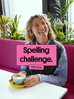 A woman with wavy blonde hair smiles up while holding a blue cup and saucer, seated at a white table. Overlaid on the image is a pink rectangle with the words Spelling challenge and Part one.