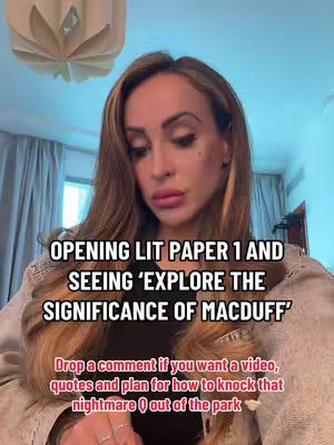 A woman with long, light brown hair is centered in the frame. She's wearing a light-colored jacket over a dark top. Text overlays appear in the image, with a light fixture visible in the top-left corner.