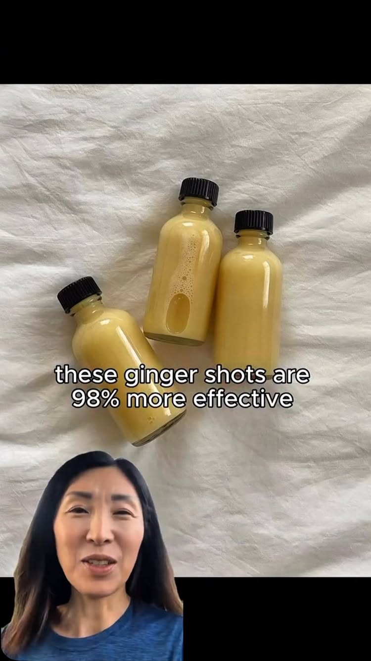 The cover image showcases three small glass bottles filled with a yellow liquid, likely some type of ginger shot, arranged on a white, textured surface, possibly fabric. The bottles are capped with black lids. The video creator's face appears in a partial inset at the bottom, looking directly at the camera. Text overlayed on the image reads, 'these ginger shots are 98% more effective'.