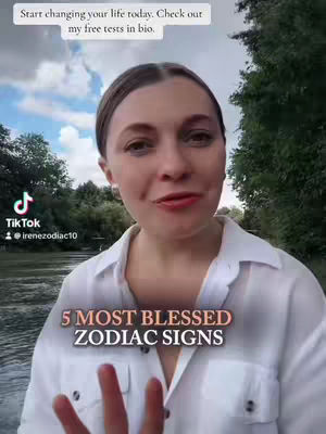 A woman with light skin and brown hair is the central subject of the image. She is outdoors, surrounded by greenery and a cloudy sky in the background. She is wearing a white button-down shirt, and the foreground shows a glimpse of her hand. The text overlay at the bottom reads '5 MOST BLESSED ZODIAC SIGNS,' suggesting a topic related to astrology.