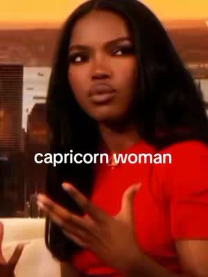 A woman with long, dark hair is centered in the frame, looking towards the left with minimal background details. Above the woman, the text "capricorn woman" is displayed in white letters.