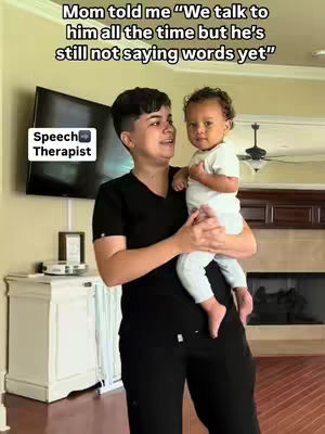 A woman in black scrubs holds a baby in the image, with a cozy living room background. Text overlays are at the top and bottom, and the woman is looking at the baby.