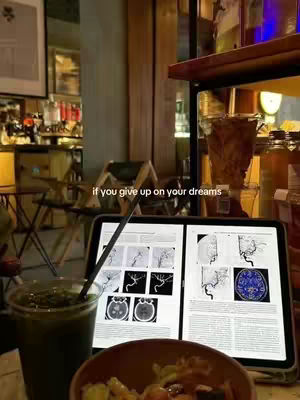 A person is studying at a cafe. They have a tablet with images on it, also a drink and a bowl are in the foreground.