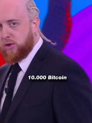 The cover image shows a man in a suit speaking, with text overlayed. The man has light skin, a full, ginger beard, and blonde braids. The background is abstract, with purple and blue hues. Text in a white box reads '10.000 Bitcoin'.