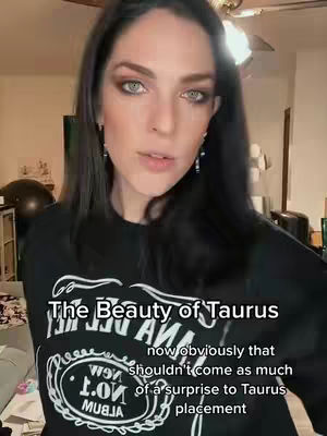 A woman with long black hair, wearing a black shirt with a graphic, directly addresses the camera. The background is blurred and suggests an interior setting. Text overlays are present, discussing astrology and beauty.