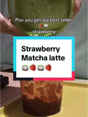 The cover image shows a clear glass with a layered drink. The bottom layer is dark, followed by a lighter, opaque layer and topped with a vibrant green liquid. Above the glass, a hand holds the glass at a slight angle, presumably adding to the visual presentation. A text box with white background and colorful borders displays the text 'Strawberry Matcha latte'. The design is simple which makes the drink the focal point.