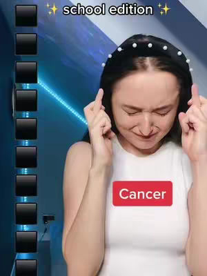 A woman with dark hair and a pearl-studded headband holds her fingers up as if crossing them, with a look of worry. A red rectangle with the word "Cancer" is situated in the middle of her white top. The background is a blurry mix of blue and white, with a vertical list of black squares to the left.