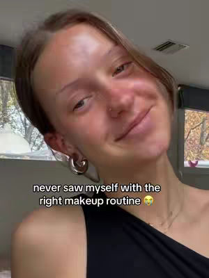 A selfie-style shot, the cover image presents a woman with light skin and brown hair, angled slightly to her right. She has hoop earrings and a nose ring. Her expression is a slight smile, and she gazes directly into the camera. The background is a subtly blurred interior setting, with text overlaid near the bottom. The lighting appears natural, and the composition is simple, focusing primarily on the woman's face and upper body.