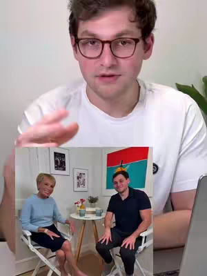 The cover image features a man in a white t-shirt and glasses partially overlaying a scene of a television interview. The scene within the overlay shows two individuals, a woman in a blue top and black skirt and a man in a black shirt and pants, seated at a small round table. The background contains simple art and decor.