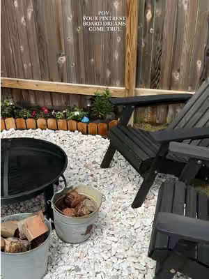 The cover image shows a backyard scene with a wooden fence in the background. In the foreground, there's a black fire pit, a wooden chair, and two buckets with logs. The ground is covered with white stones. The text overlayed says \"POV: YOUR PINTEREST BOARD DREAMS COME TRUE\".