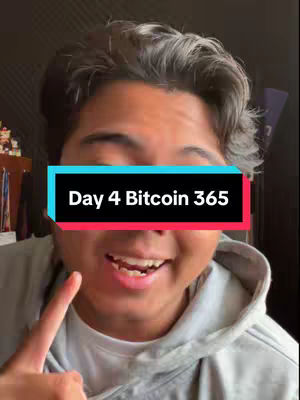 A man with short, dark hair is smiling while pointing his index finger with a hook on his face that reads Day 4 Bitcoin 365. He is wearing a grey hoodie and standing in front of a dark background.