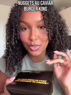 A woman with curly hair holds a Burger King box, with text overlay that reads 'NUGGETS AU CAVIAR BURGER KING'. She looks at the camera with her tongue out.