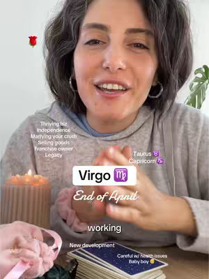 A woman with grey curly hair is centered, looking slightly up and to the right with a pleasant facial expression. She's wearing a grey hoodie, and her hands are clasped in front of her. Various text elements overlay the image, along with small graphics such as a red rose near the top left.. A lit candle and a deck of cards are visible in the foreground.