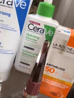 The image shows a collection of skin care products. The products are from CeraVe, La Roche-Posay, and Fenty Beauty and arranged on a reflective surface. The perspective is close-up, focusing on the products.
