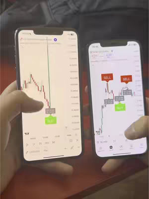 The image shows two smartphones side by side, each displaying trading charts on their screens. The left screen displays a downward-sloping trend in red, with a green 'BUY' button at the bottom. The right screen shows a more complex chart with 'SELL' and 'BUY' indicators. The background environment is blurred but seems to be indoors.