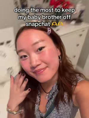 A selfie-style image with a young woman as the central focus. She has long brown hair with a lavender barrette. The text overlay reads: "doing the most to keep my baby brother off Snapchat."