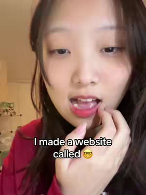 A close-up shot of a young woman with dark hair looking at the camera with her mouth slightly open. She is wearing a red top, and her right hand is near her mouth. Text overlay at the bottom indicates a website is mentioned.