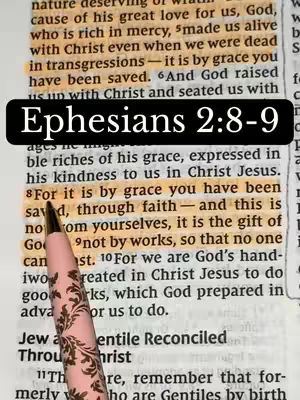 The image showcases a close-up of a bible verse, with highlighted text and a pen resting on it. The main focus is on a passage from Ephesians 2:8-9, highlighted in yellow, with a pen diagonally overlayed. Overlaid on top is a black rectangular bar that has the text, "Ephesians 2:8-9". The background shows the texture of the bible page, with visible text and aged paper tones.