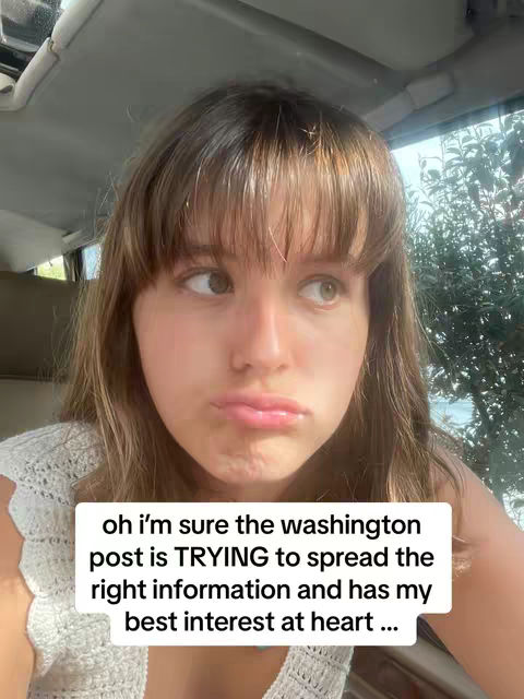 A close-up selfie of a young woman in a car, looking slightly off-center with a subtle pout. She has light skin, medium-length brown hair with bangs, and is wearing a white top. A text overlay in a white box gives a sarcastic statement relating to the Washington Post.
