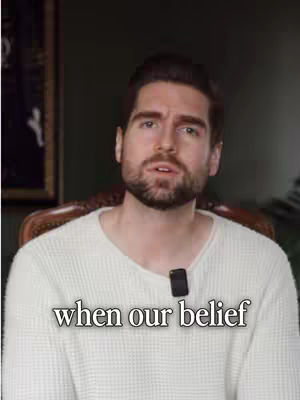 A man with a beard and white sweater is the focus of the image, seated and facing the camera with text overlayed at the bottom.