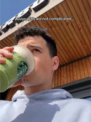 A young man is drinking from a Starbucks cup, with a green beverage visible. The background features a building facade with wooden paneling and a blue sky. Text overlay is placed at the top of the image.