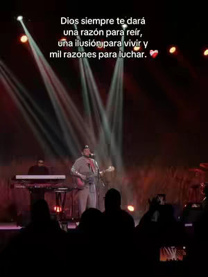 The image features a man playing a guitar on a stage with stage lights and an audience. Text overlayed reads a motivational quote.