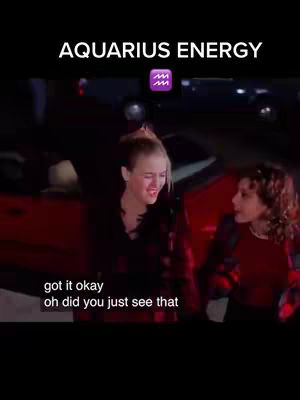 A cover image from the movie Clueless, shows two young women, one with blonde hair and a plaid shirt, the other with brown hair and a red top, reacting while in what appears to be a vehicle. Text overlays at the top says 'Aquarius Energy' with an Aquarius symbol, and at the bottom the subtitles reads 'got it okay, oh did you just see that'.