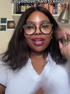 A woman with dark hair and glasses is centered in the frame, speaking. Above her head, the text "Easy to love, hard to keep" is displayed. Behind her, a bookcase is visible.